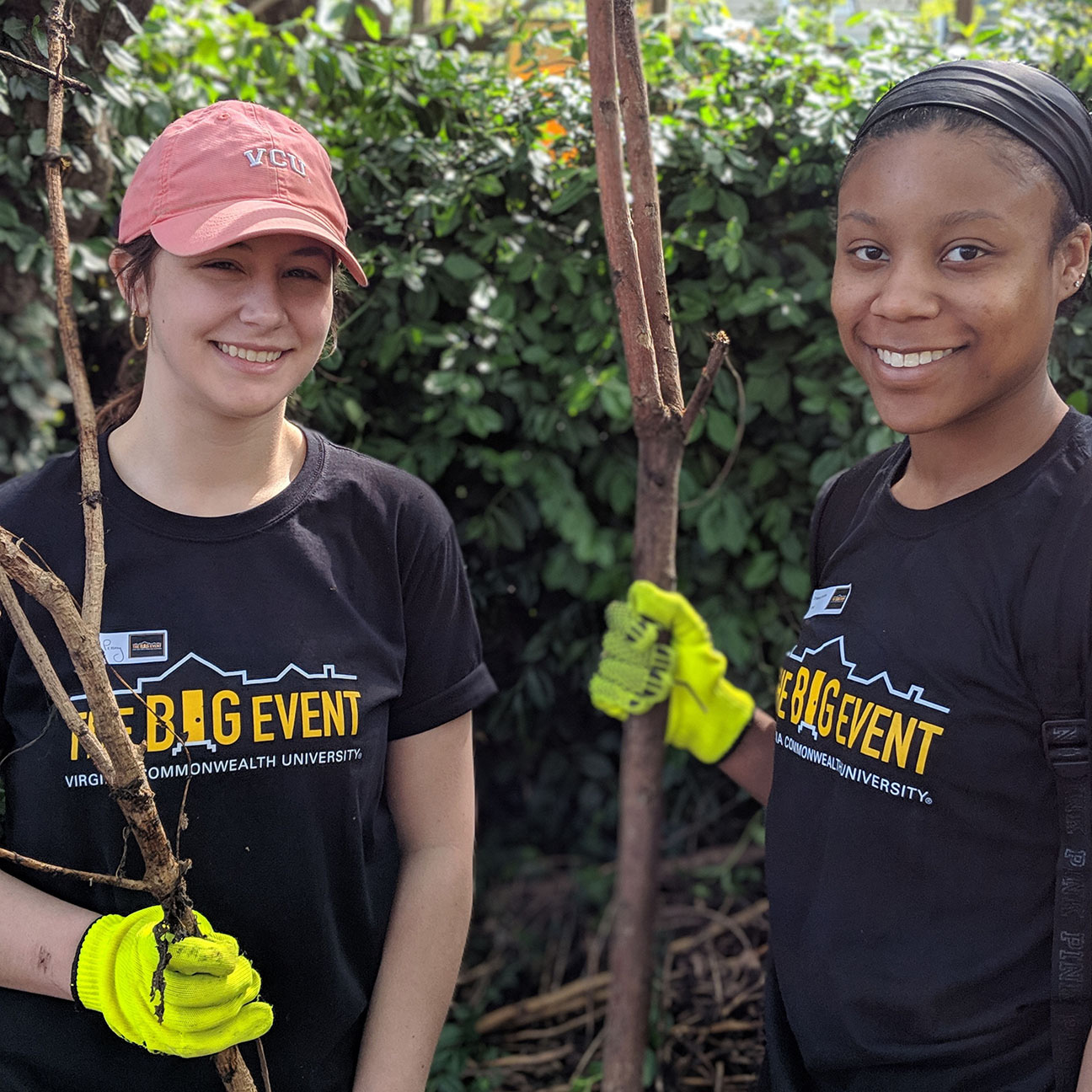 Two student volunteers holding large sticks