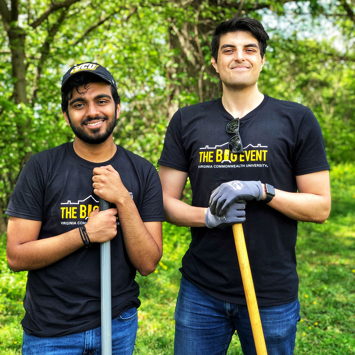 Two male students standing outside holding gardening tools